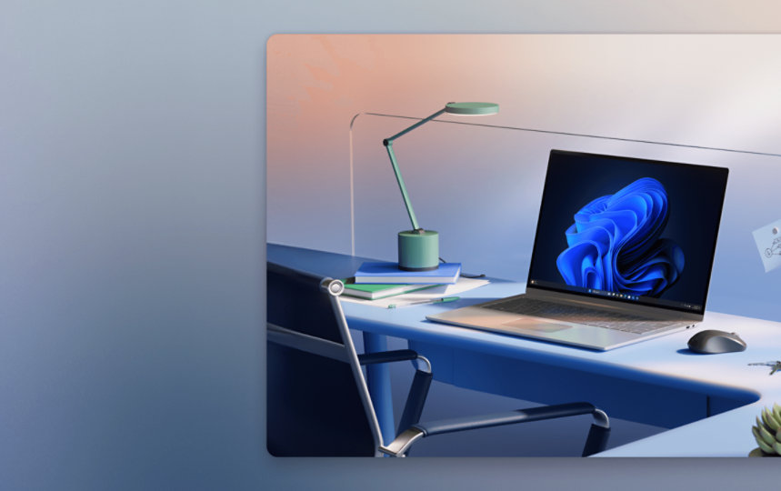 Modern desk setup with a laptop showing abstract art, two books, a green lamp, sticky notes on a divider, and a mouse on the right.